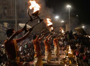 Evening Ganga Aarti ceremony at varanasi Ghat with priests holding flaming torches.